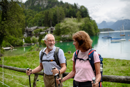 Portrait of active elderly couple hiking together in autumn mountains. Senior tourists looking at lake