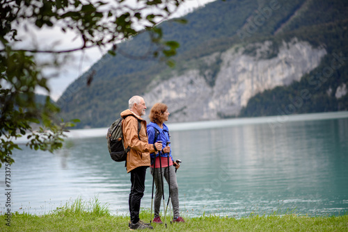 Portrait of beautiful active elderly couple hiking together in autumn mountains. Senior tourists looking at lake. © Halfpoint