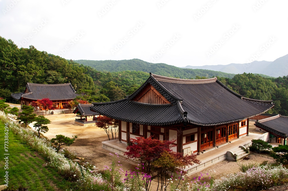 Example of traditional Korean temple architecture. A Buddhist temple in Korea. A wooden building with a tiled roof and intricate ornaments adorning its facade stands serenely amidst a tranquil landsca
