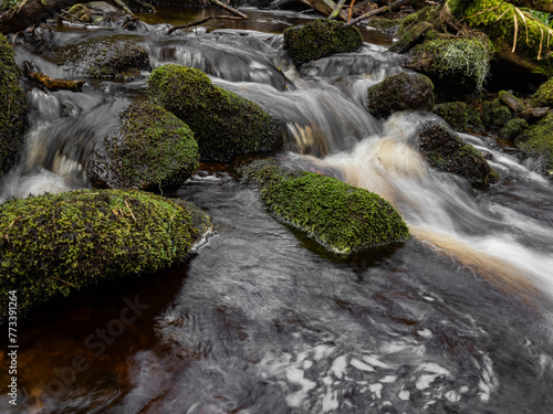 Mountain river in England, dreamy scenery, moss-covered stones and beautiful waterfall in the forest. Sunny creek in spring cloudy Yorkshire evening. small cascade surrounded by moss and autumn leaves