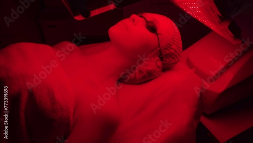 LED red cosmetic light is treating the facial skin of a young woman.