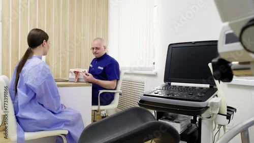 Consultation and examination with a gynecologist. A gynecologist explains changes in the ovaries to a patient using an artificial model of the uterus.