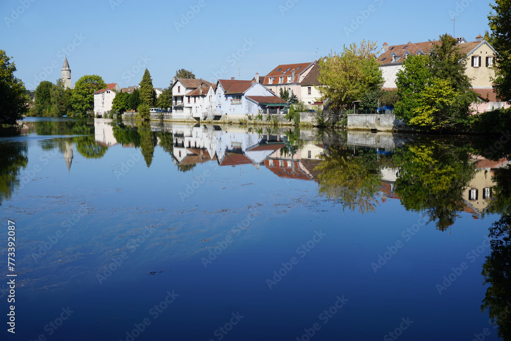 mirror reflection of the buildings and trees in the river in Audincourt, eastern France