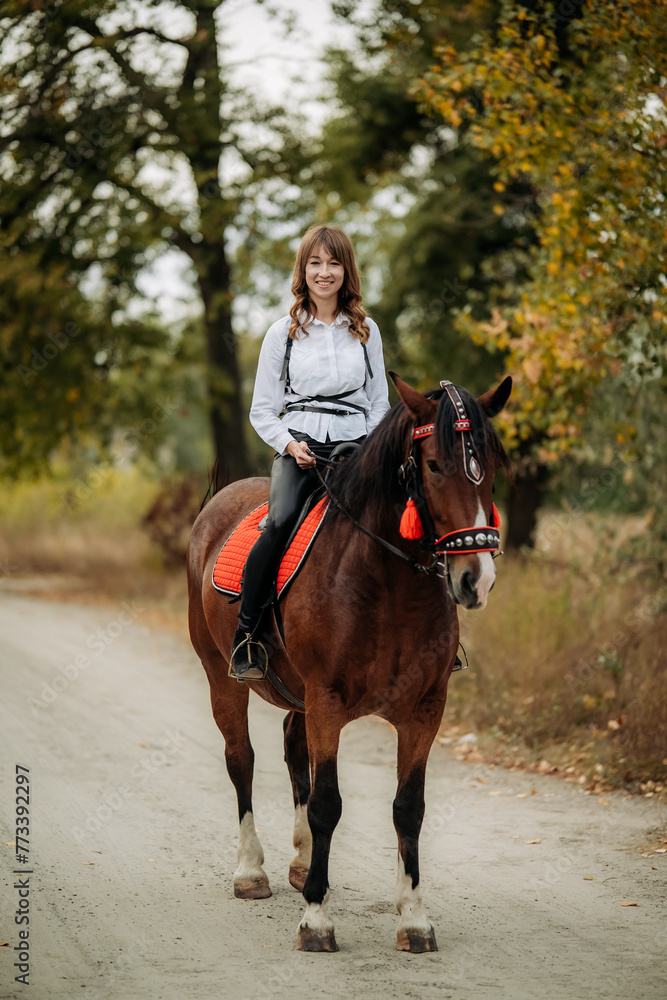 A girl in a white shirt and hat sits on a beautiful brown horse. A girl in a white shirt and hat sits on a beautiful brown horse.
