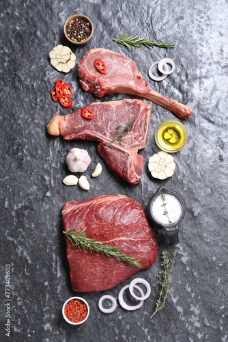 Fresh raw beef cuts and different spices on grey textured table, flat lay