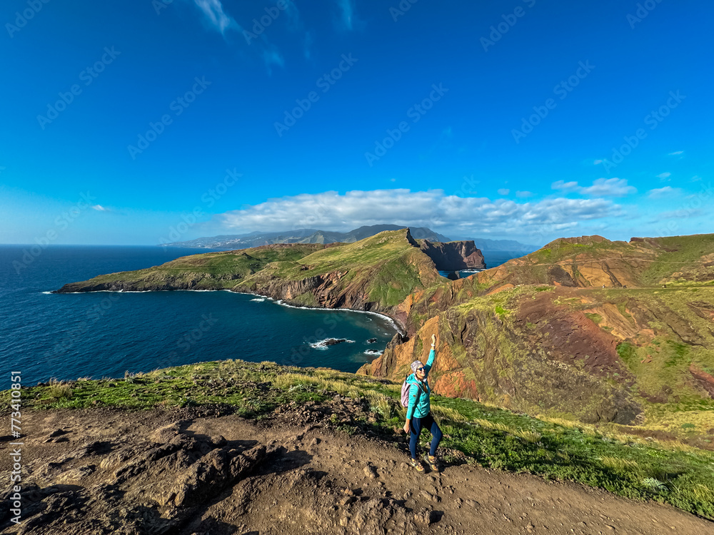 Hiker woman on idyllic hiking trail along rocky rugged cliffs at Ponta de Sao Lourenco peninsula, Canical, Madeira island, Portugal, Europe. Rugged terrain of coastline of Atlantic Ocean. Wanderlust