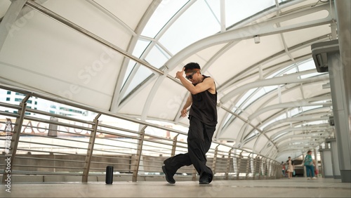 Skilled handsome hipster perform street dancing at narrow corridor. Professional hip hop dancer show b-boy step at corridor at urban city while wearing stylish cloth. Outdoor sport 2024. Sprightly. © Summit Art Creations