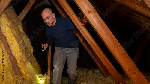 Home inspector inspecting condition of home attic and finding moisture on the ceiling.