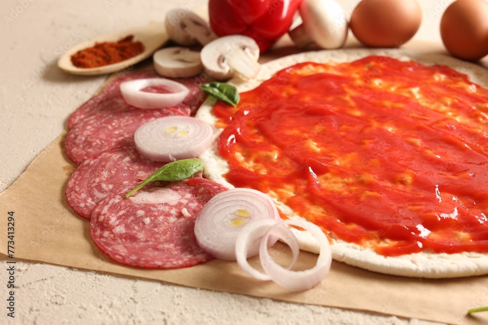 Pizza base smeared with tomato sauce and products on light textured table, closeup Pizza base smeared with tomato sauce and products on light textured table, closeup
