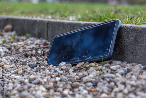 A smartphone with a broken display on stones. Damage to the phone screen. Lost phone