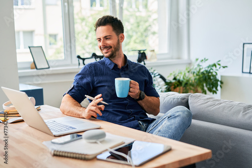 Relaxed man with cup of coffee working at home office