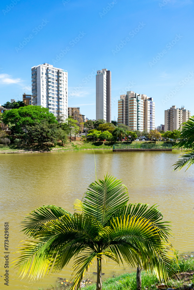 Residential buildings on the edge of a lake with many trees. Blue sky with clouds. City of Belo Horizonte. Brazil