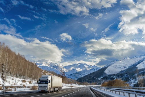 White truck cargo lorry on highway road in mountain landscape with snow mountains and blue sky