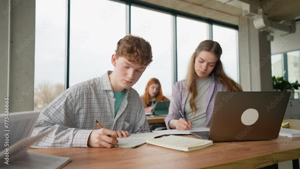 Focused young students taking notes from laptop Focused young students taking notes from laptop