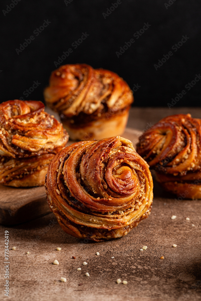 Homemade cruffins, a hybrid of a croissant and a muffin, filled with mix of butter, brown sugar and nuts. Baked in a muffin mould. Vertical image, dark background, copy space.