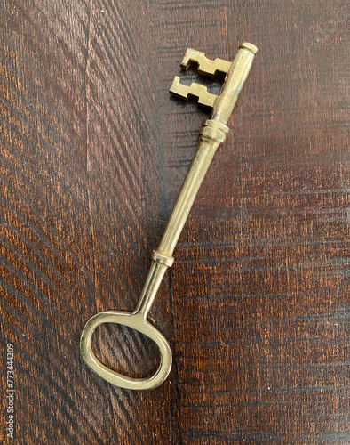 Old metal key. Antique golden key on a wooden background.