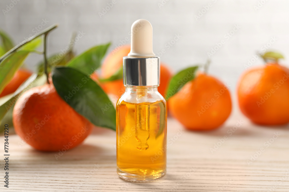 Bottle of tangerine essential oil and fresh fruits on white wooden table, closeup Bottle of tangerine essential oil and fresh fruits on white wooden table, closeup
