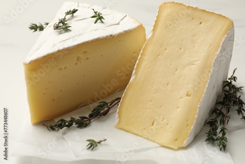 Pieces of tasty camembert cheese and thyme on white table, closeup