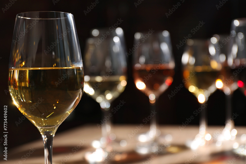 Tasty white wine in glass against blurred background, space for text Tasty white wine in glass against blurred background, space for text