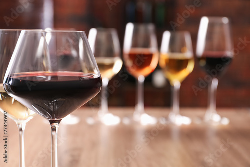 Tasty red and white wines in glasses against blurred background, space for text