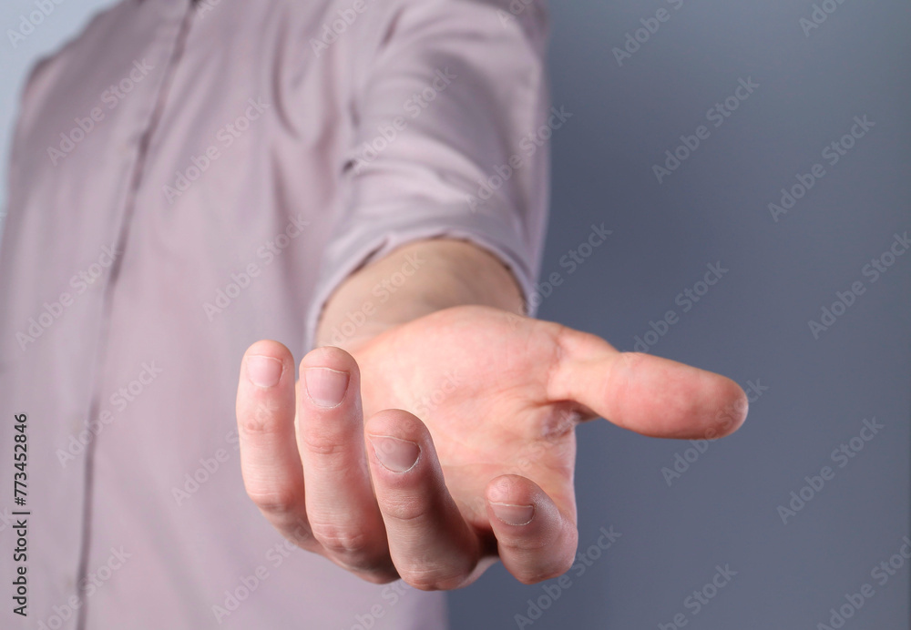 Man holding something in his hand on grey background, closeup Man holding something in his hand on grey background, closeup