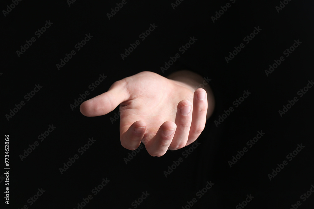 Man holding something in his hand on black background, closeup Man holding something in his hand on black background, closeup