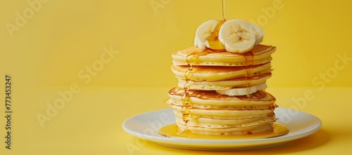A stack of pancakes with banana and honey drizzled on top, with a white plate underneath against an isolated pastel yellow background Generative AI