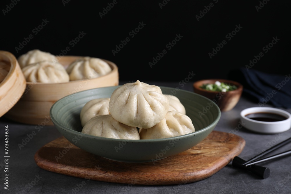 Delicious bao buns (baozi) in bowl on grey table, closeup Delicious bao buns (baozi) in bowl on grey table, closeup