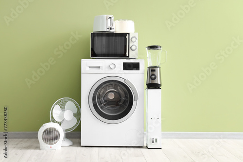 Modern household appliances near light green wall in room