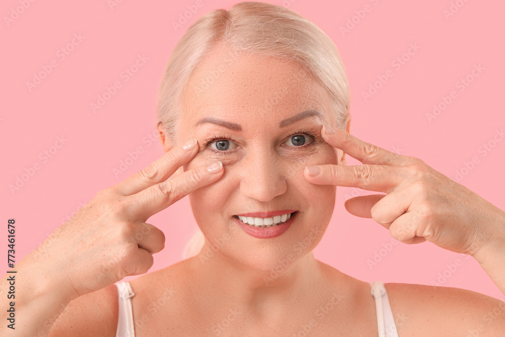 Beautiful mature woman doing facial massage on pink background, closeup Beautiful mature woman doing facial massage on pink background, closeup