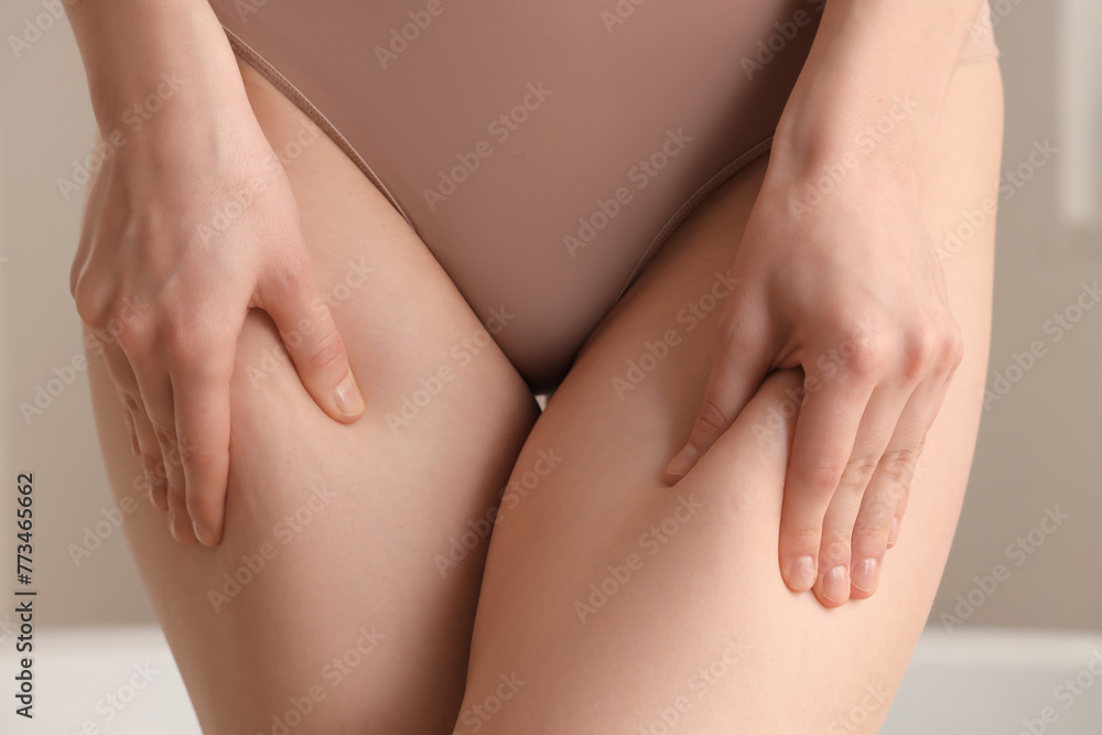 Beautiful young woman with hips cellulite problem in bathroom, closeup Beautiful young woman with hips cellulite problem in bathroom, closeup