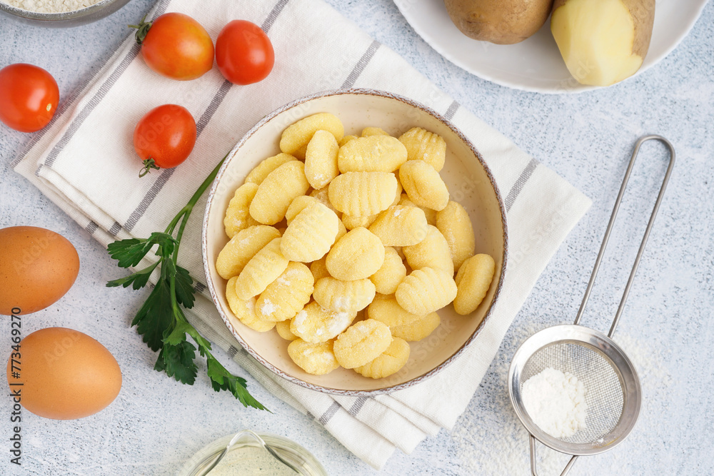 Bowl with tasty gnocchi, tomatoes and parsley on light background Bowl with tasty gnocchi, tomatoes and parsley on light background