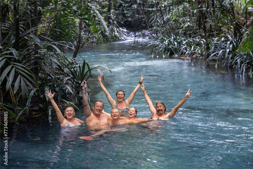 A group of friends happily posing in a beautiful blue river, Waigeo Island, Indonesia photo