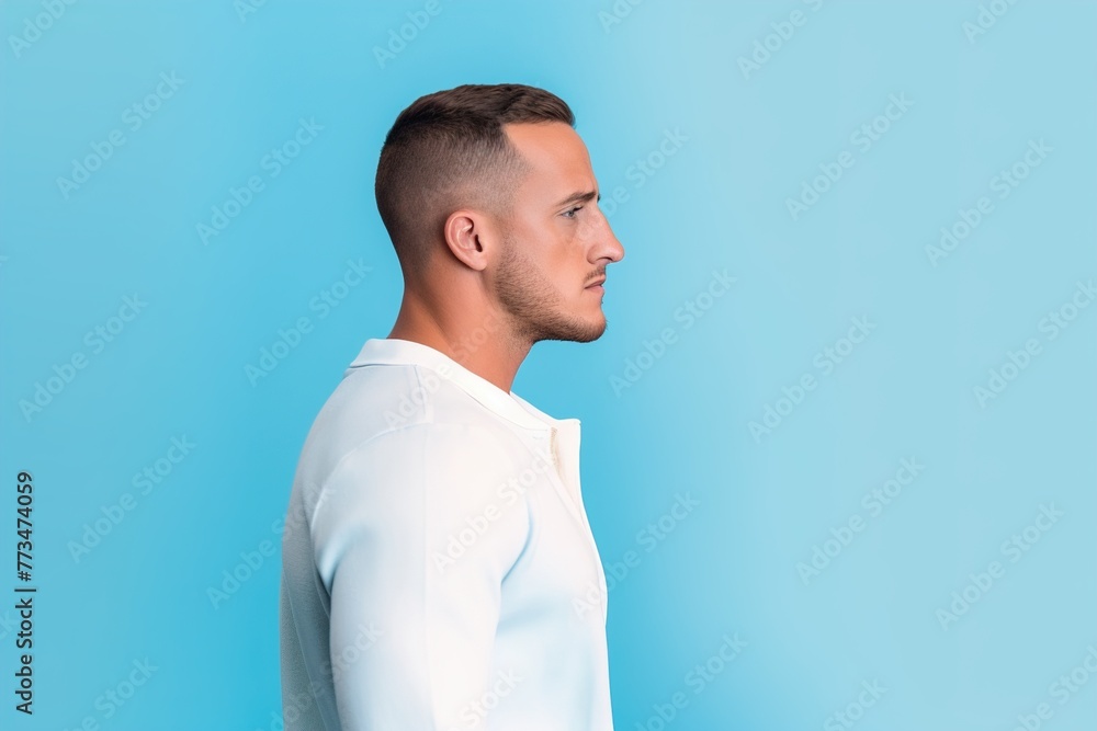 A man with a shaved head and a beard stands in front of a blue wall A man with a shaved head and a beard stands in front of a blue wall