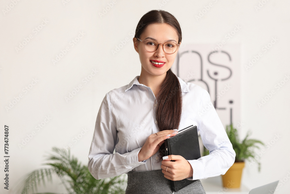 Young Asian businesswoman with notebook in office Young Asian businesswoman with notebook in office