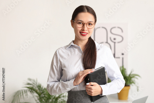 Young Asian businesswoman with notebook in office