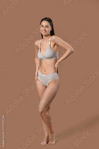 Slim young woman in cotton underwear on brown background