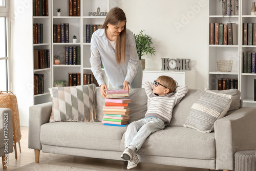 Cute little boy and his mother with different books at home