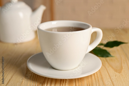 Tasty tea in cup on light wooden table, closeup