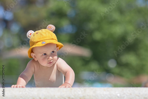 A small child next to the pool in a cap