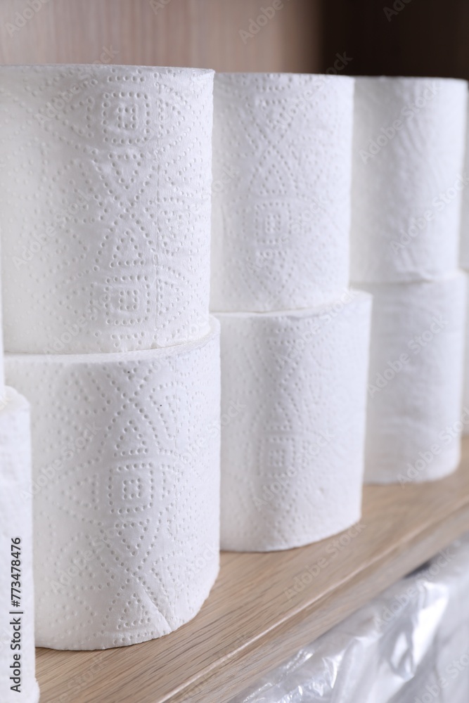 Fototapeta premium Stacked toilet paper rolls on wooden shelf