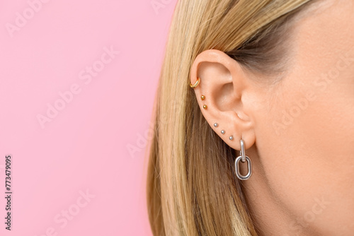 Schilderij op canvas Woman with multiple ear piercing on pink background, closeup