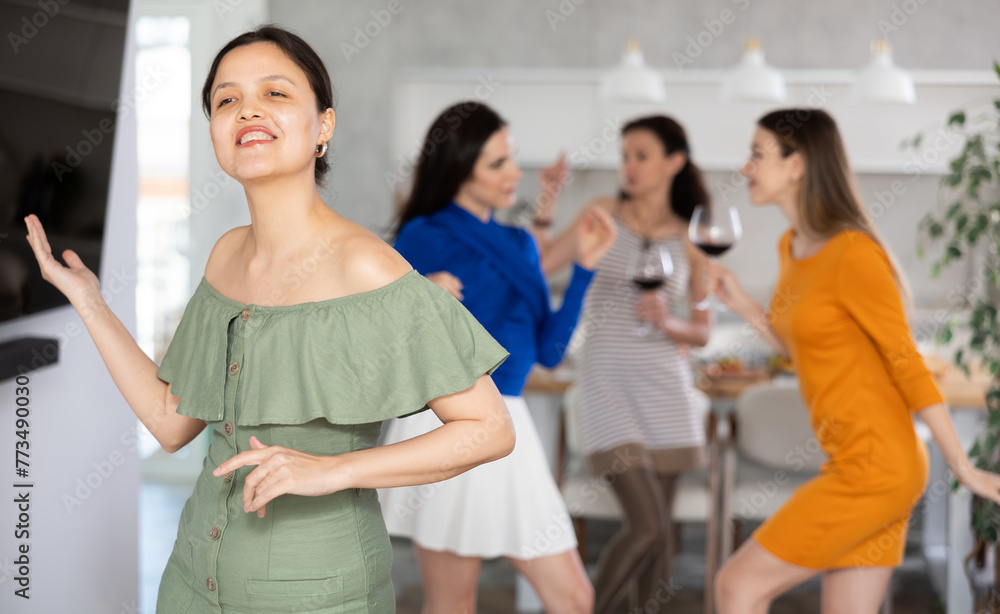 Group of women friends dancing at party in kitchen at home..