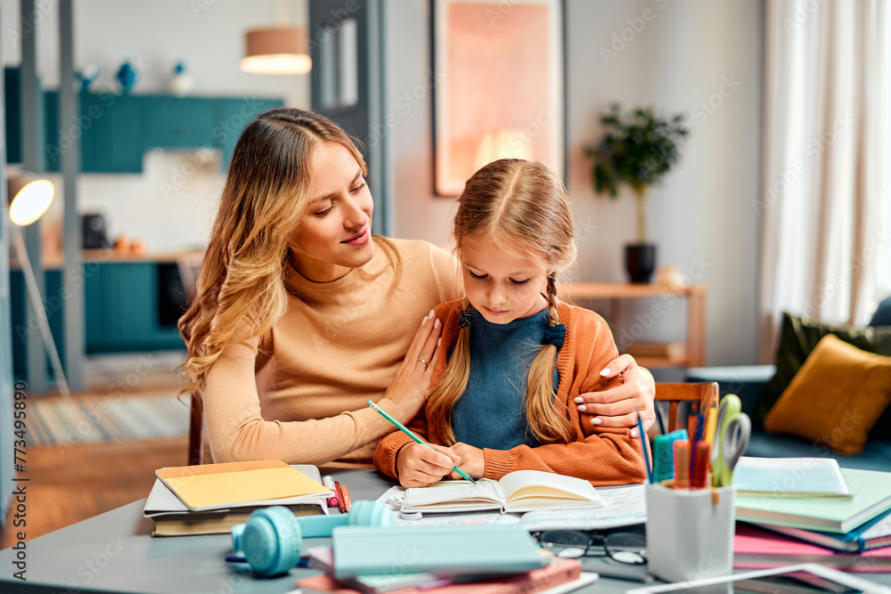 Concept of family support. Caring mother sitting next to daughter and embracing her tenderly by desk Concept of family support. Caring mother sitting next to daughter and embracing her tenderly by desk