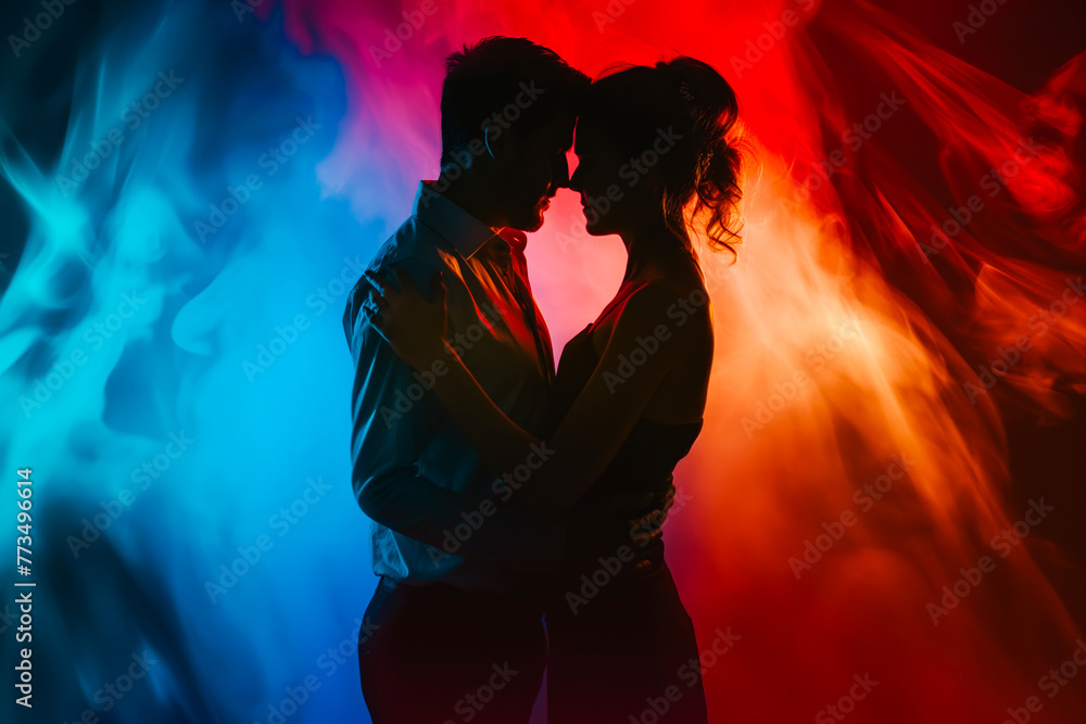 Side view silhouette of young couple dancing against colored dramatic background.
