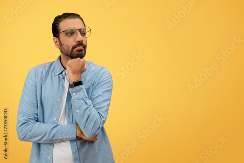Thoughtful man with hand on chin, denim shirt photo