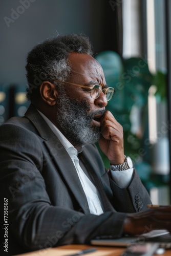 A man in a suit sitting at a table with a laptop. Ideal for business and technology concepts