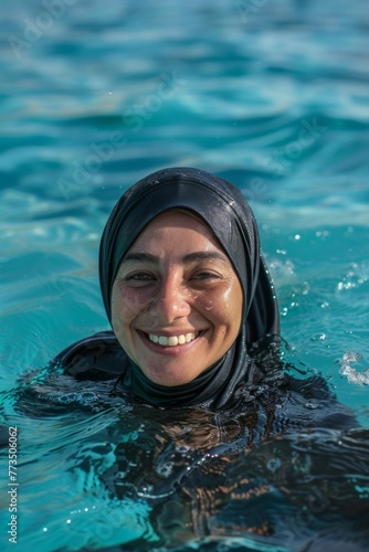 Gleeful Muslim adult woman on her 40th in swim hijab (burkini), embodying water fun and cultural freedom