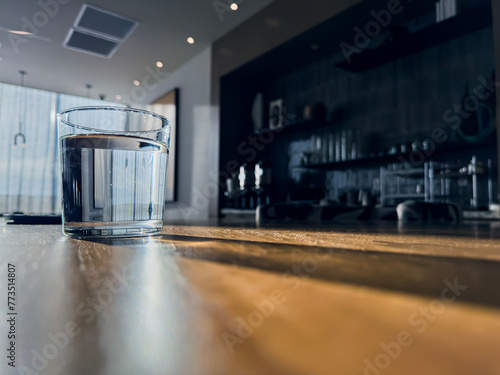 A glass of water on the table. Natural sunlight shines from behind.