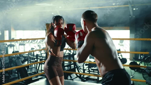 A focused female boxer and her trainer engage in a rigorous boxing workout, exchanging techniques and punches in a specialized boxing ring of the gym. Camera 8K RAW. photo